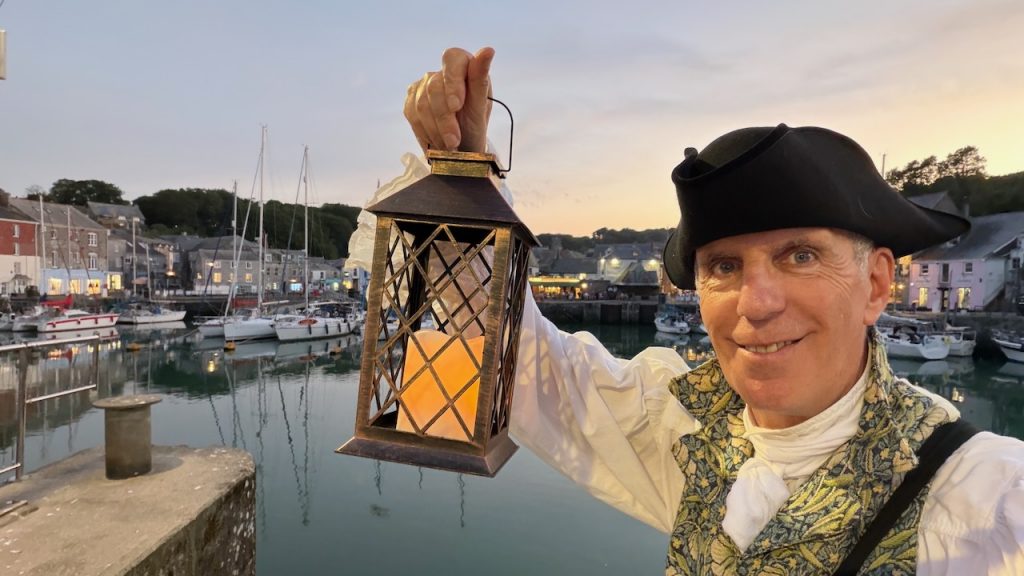 Man holding lantern in front of Padstow Harbour